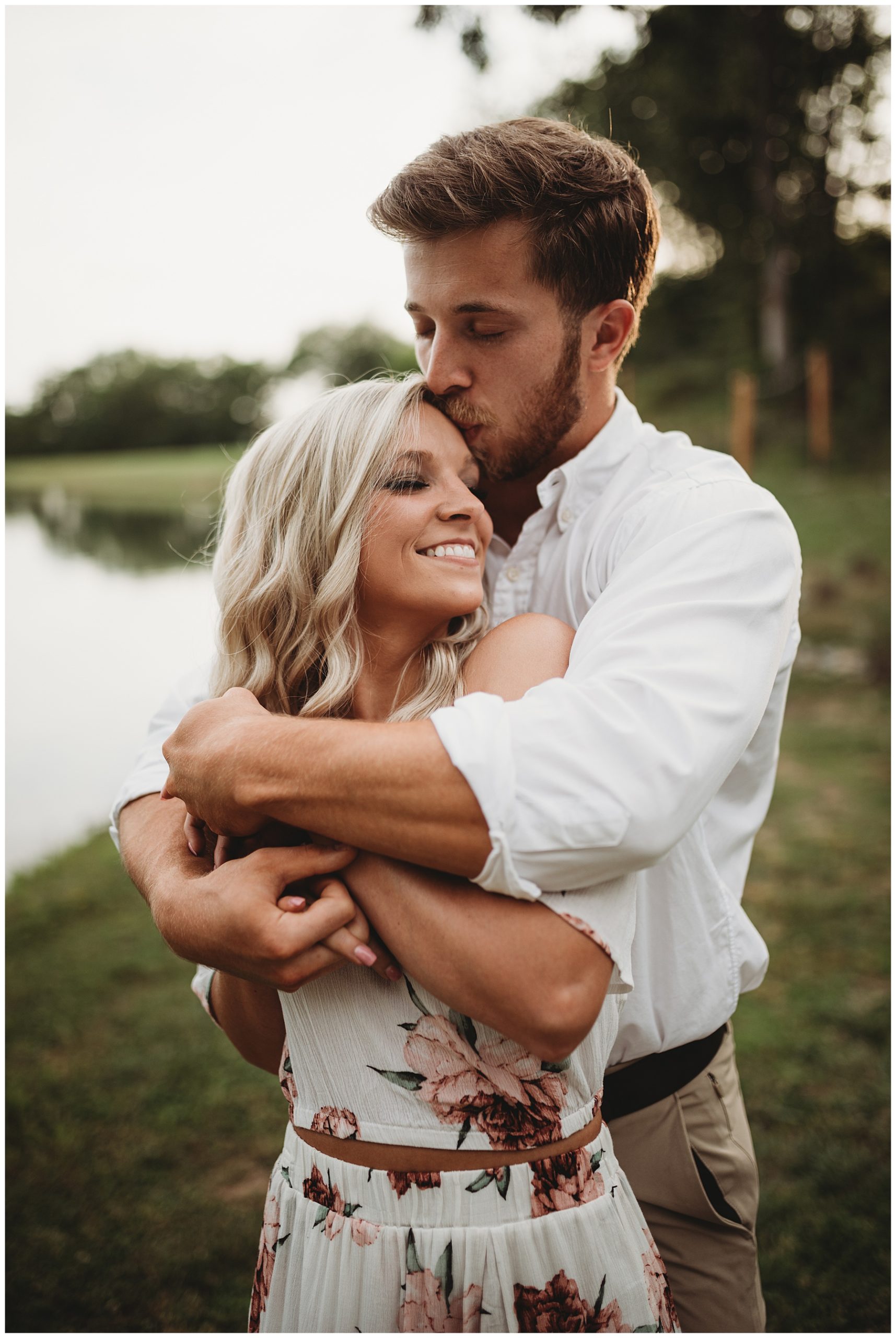 Man and woman hugging near Nashville lake during summertime engagement session