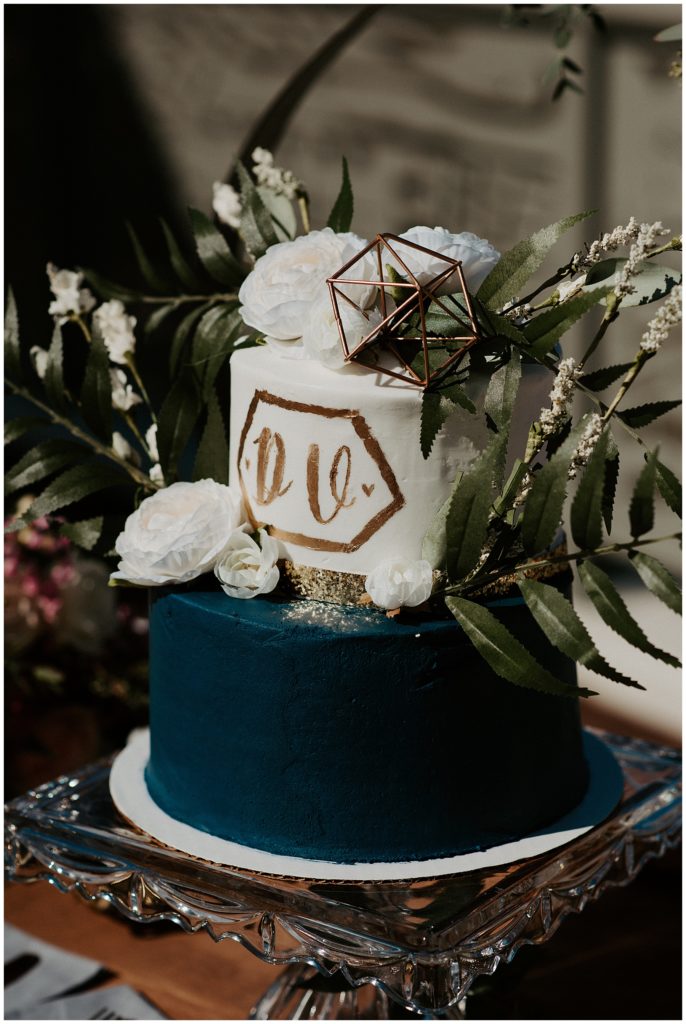 white, gold, and navy wedding cake with geometric feature on top