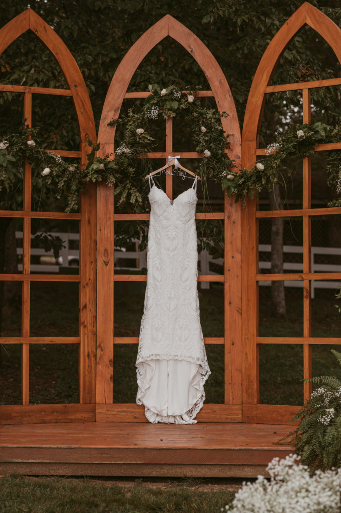 wedding dress hanging on outdoor wedding venue alter