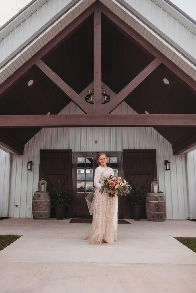 bride standing outside of barn at white oaks venue before wedding ceremony in Kentucky