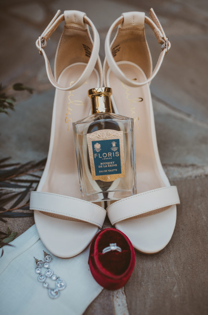 bride's shoes, perfume, and ring all in details shot for wedding day