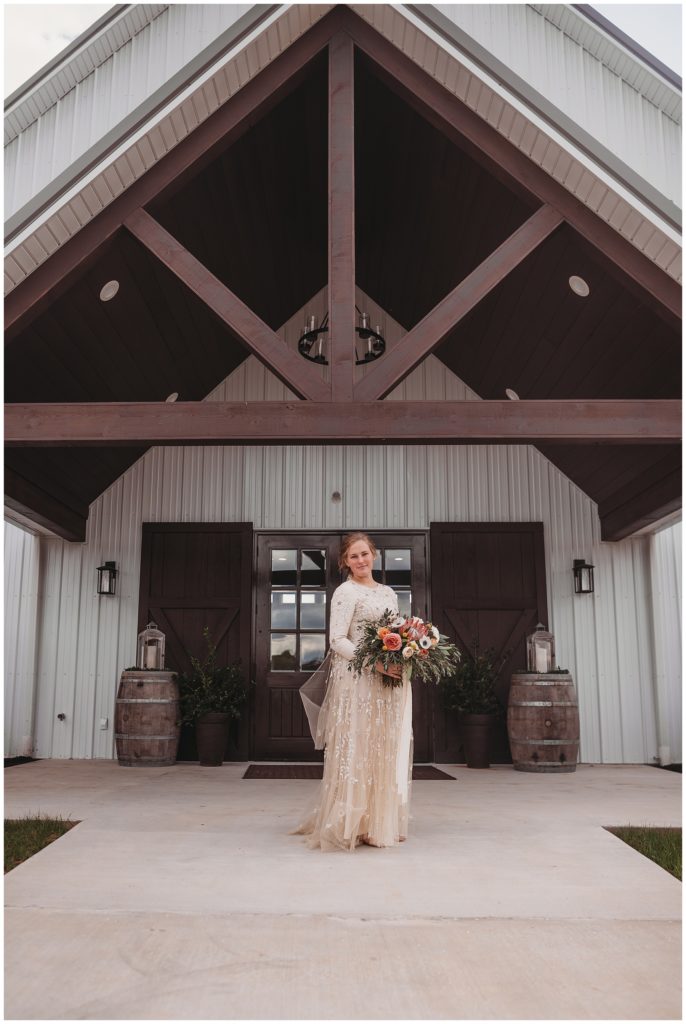 bride standing in front of barn on wedding day
