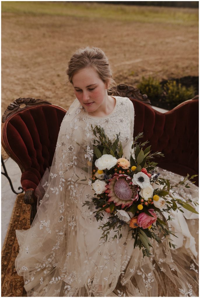 bride sitting on couch holding bridal bouquet