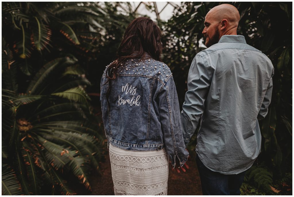 bride and groom holding hands wearing matching jean jackets