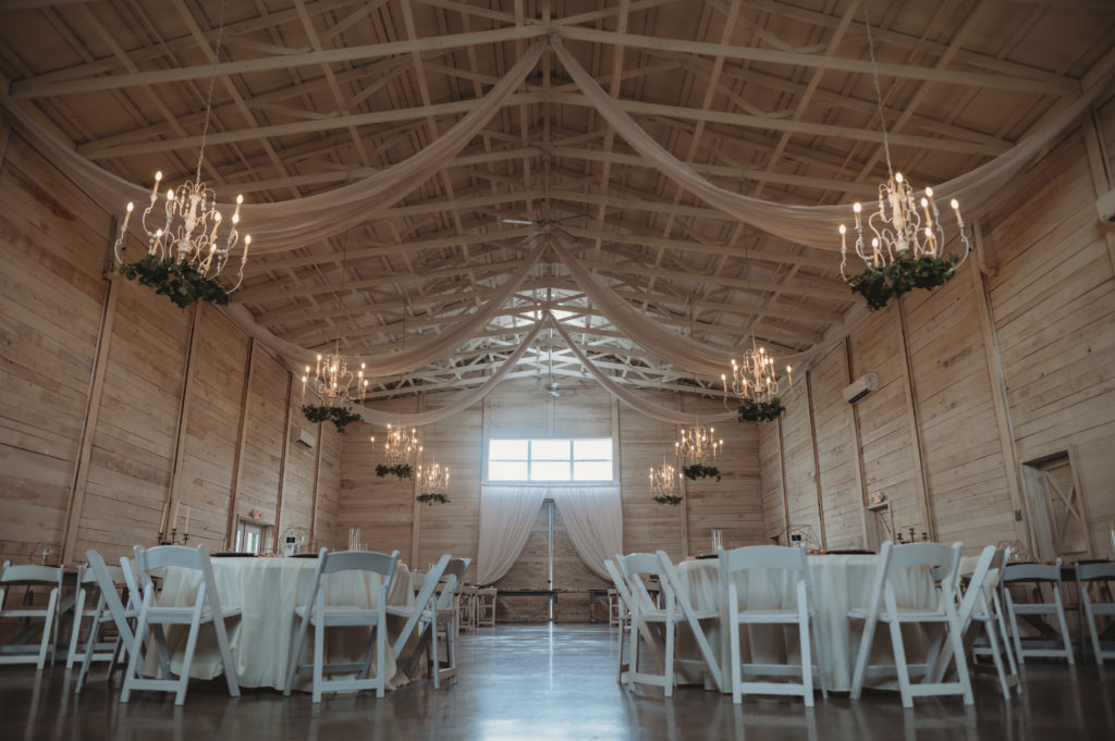 inside the White Dove Barn in Beechgrove, Tennessee. Gorgeous reception space in a barn, with white chandeliers and cream draping.