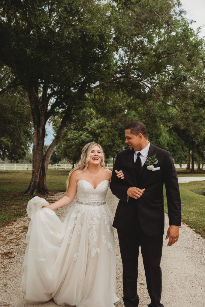 bride and groom walking towards the camera in Vero Beach laughing on a lush trail.