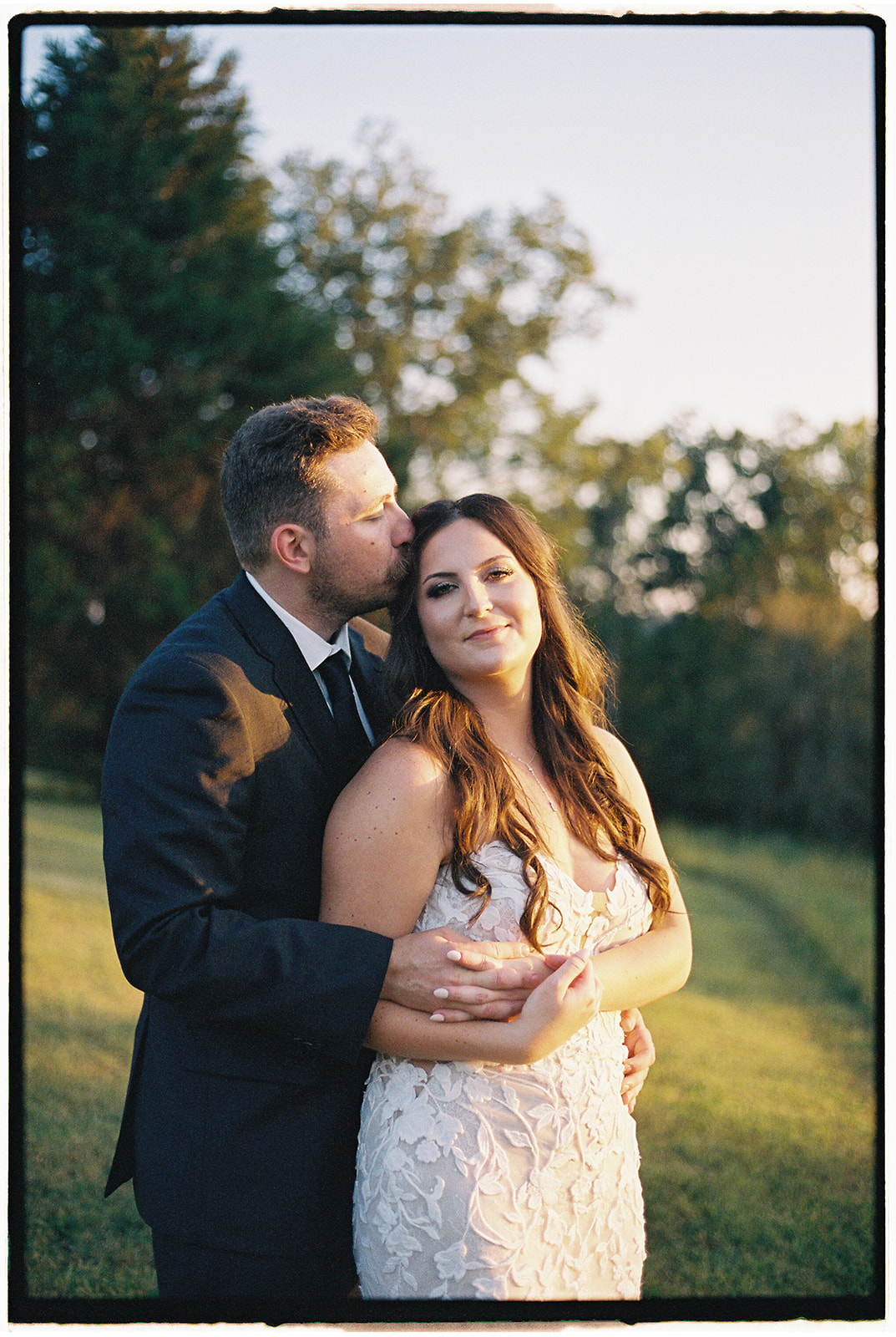 Newlyweds stand together in a field in a film photo from a Hybrid Wedding Photography