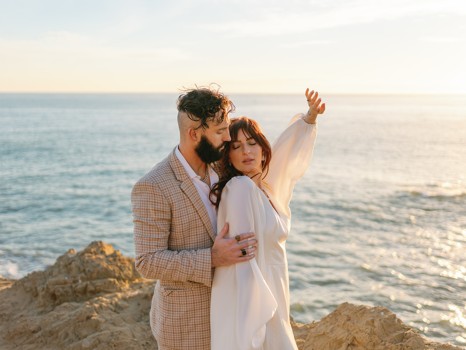 A bride and groom dance together on a rocky oceanside cliff at one of the San Francisco Wedding Venues