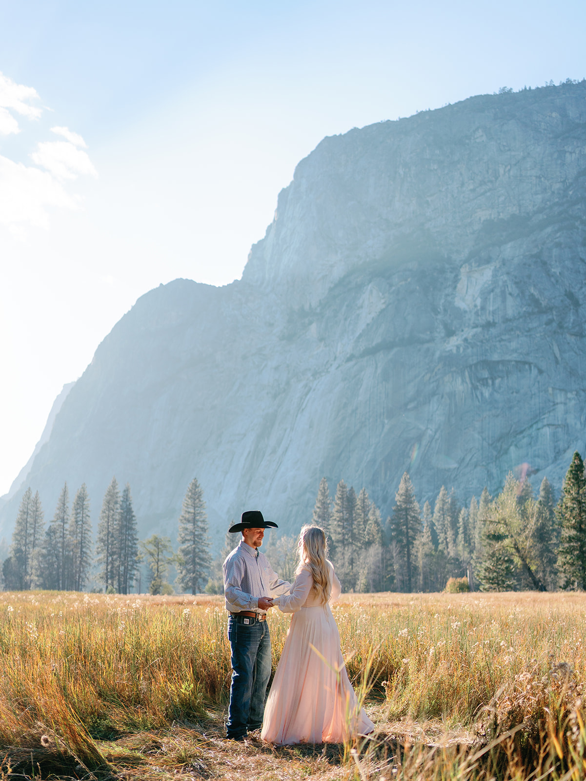 Newlyweds dance in a field of tall golden grass by a mountain at a Yosemite National Park Wedding