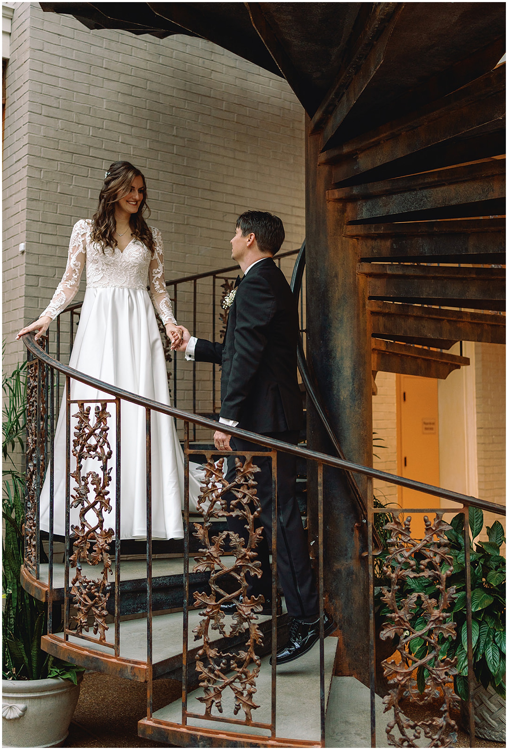 A groom leads his bride down an iron spiral staircase at their gaylord opryland wedding