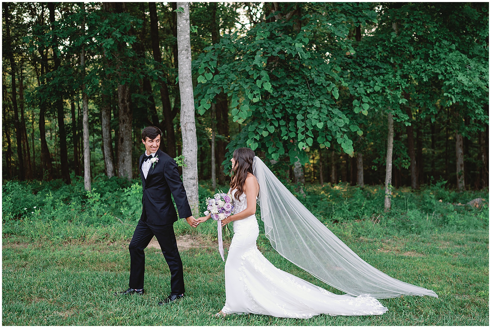 A groom in a black tuxedo leads his bride through a forest trail by the hand at hickory meadow charlotte tn