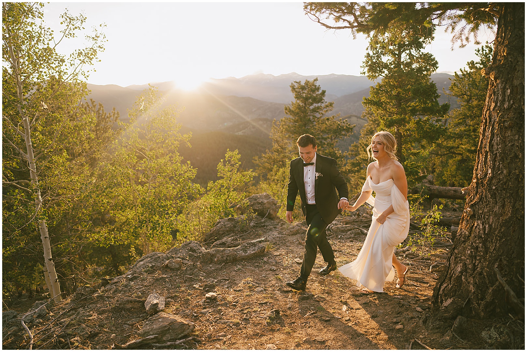 A groom laughs with his bride as he leads her up a mountain trail at their north star gatherings wedding