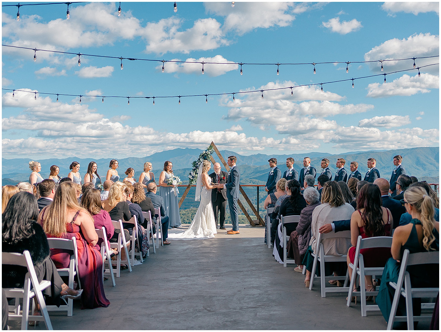 Newlyweds stand on an outdoor patio for their wedding ceremony holding hands overlooking the mountains at the trillium venue