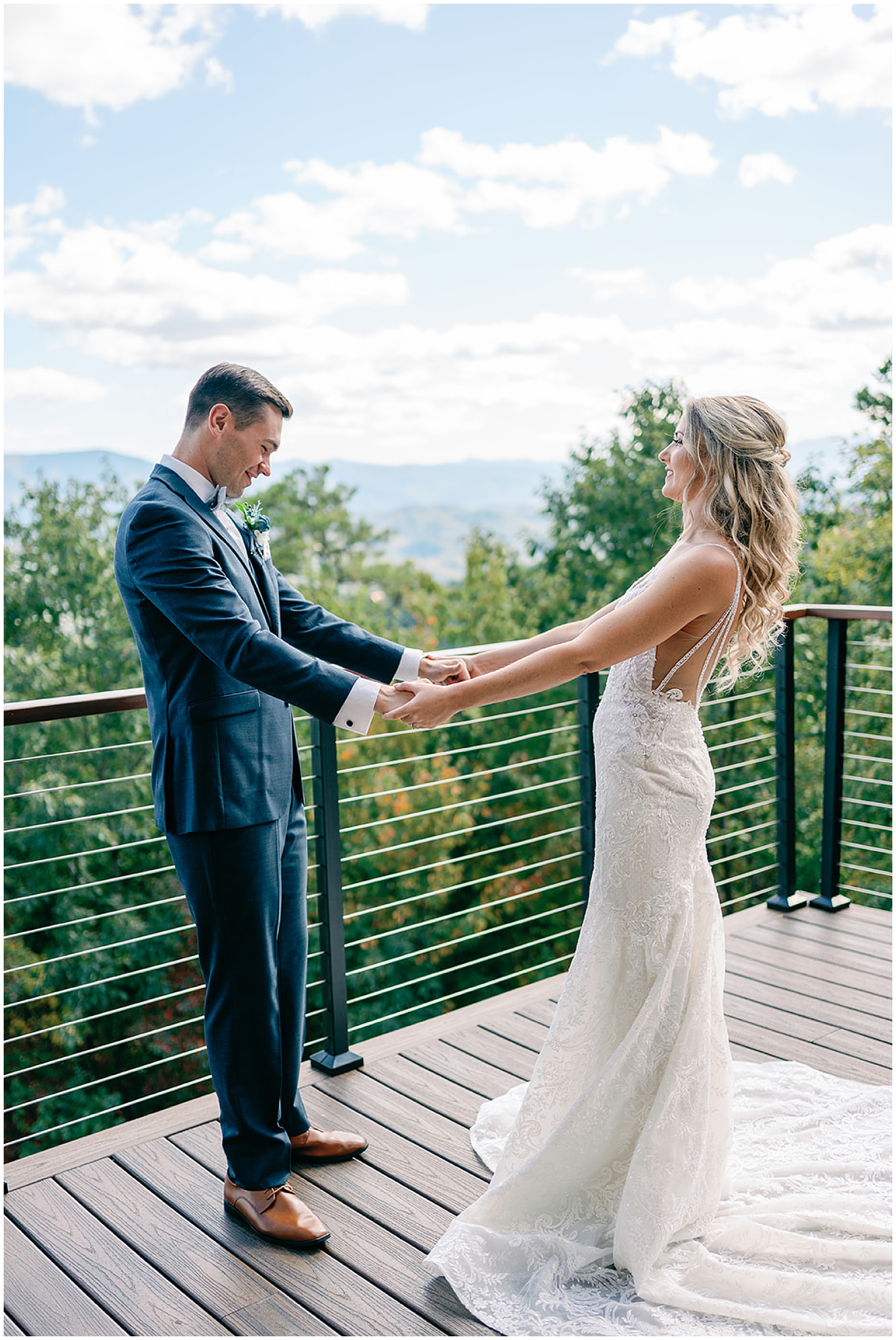 A groom holds hands and smiles while seeing his bride for the first time during their first look on an large mountain deck