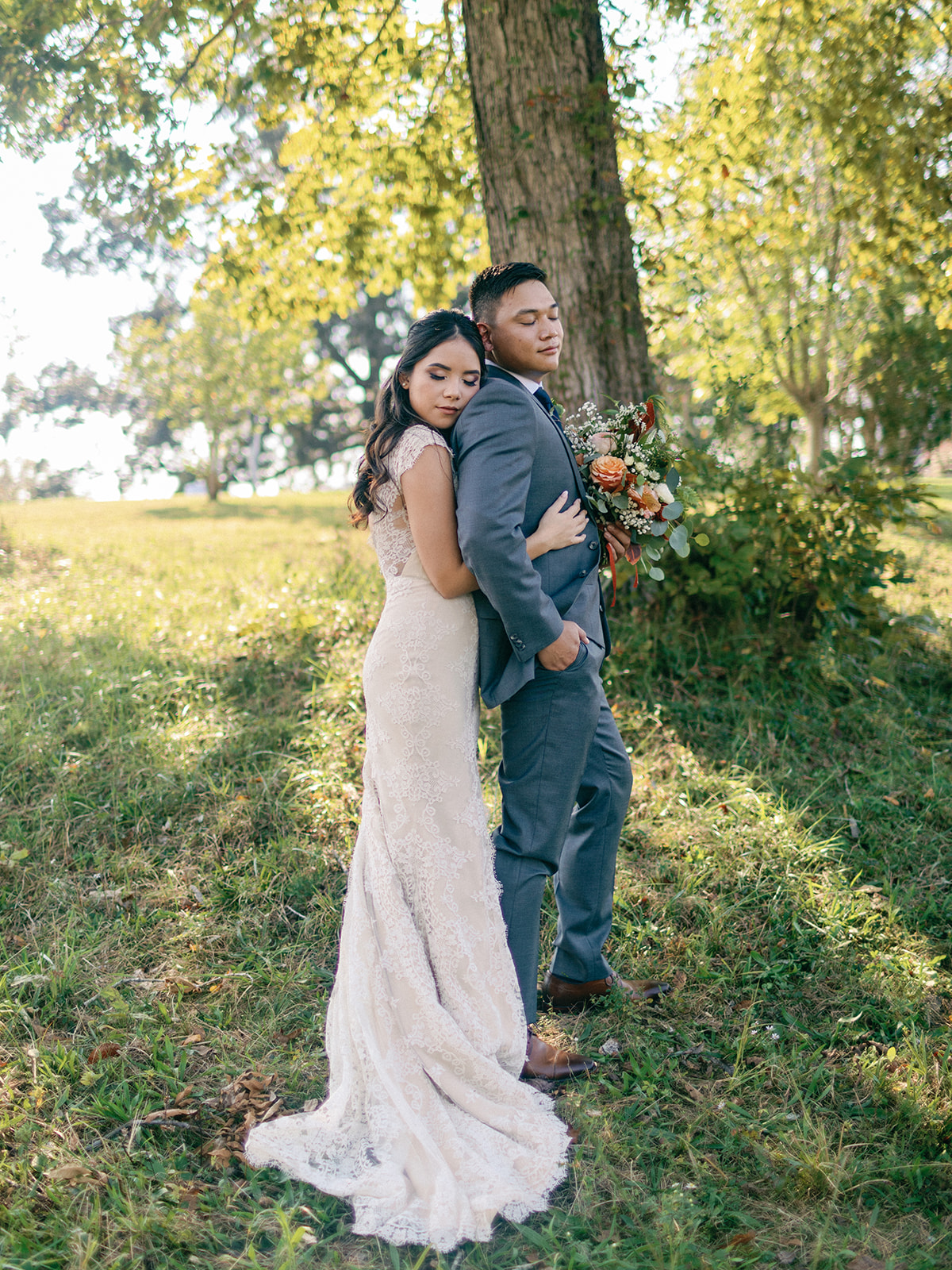 Newlyweds hug and stand under a tree