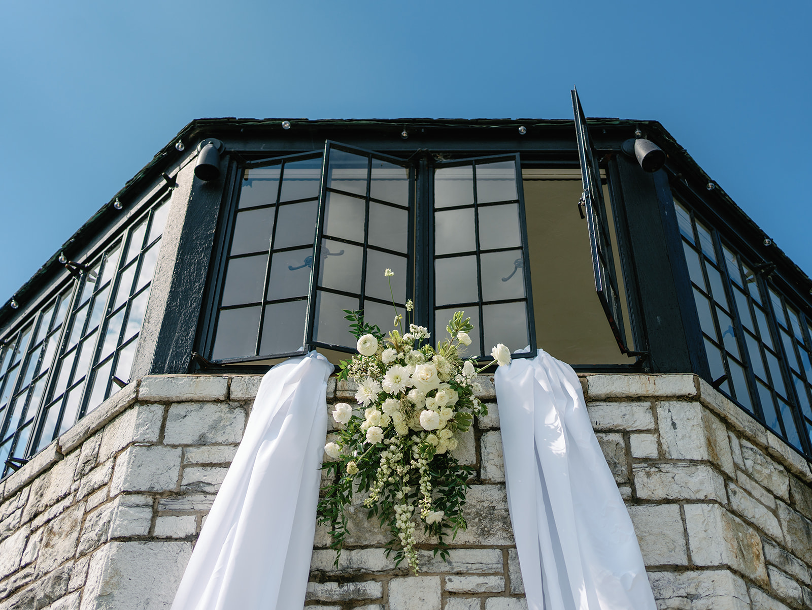 Details of a floral arrangement and white linens hanging out of a window at a Kincaid House Wedding