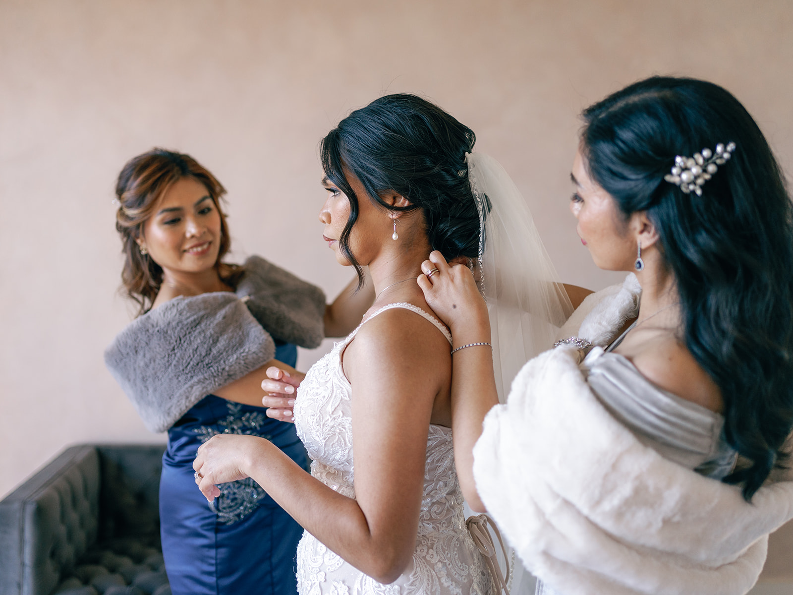 A bride stands in the getting ready room while her bridesmaids help her get ready at her The magnolia wedding