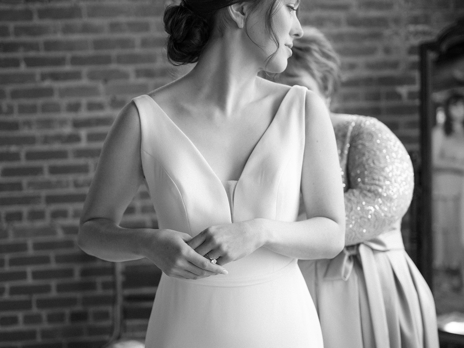 A bride stands in her dress as her mom zips it up behind her at The Standard Wedding Venue