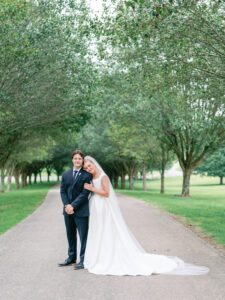 Bride and groom in a classic wedding portrait amongst a tree lined drive.